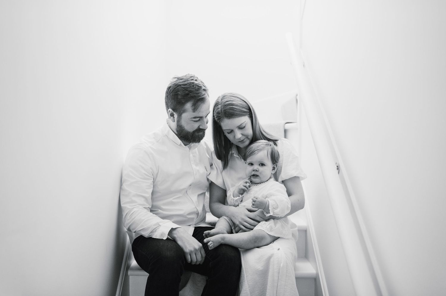 Black and white photo showing tender moments between parent and child in a minimalist setting.