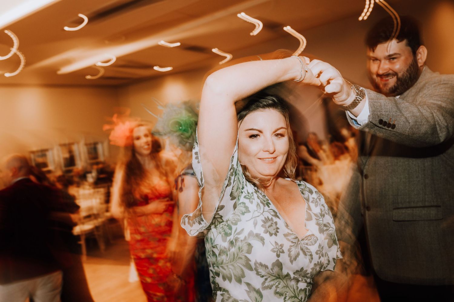 Lively dance floor scene with warm lighting during wedding reception celebrations. Meldrum House Wedding Photography.