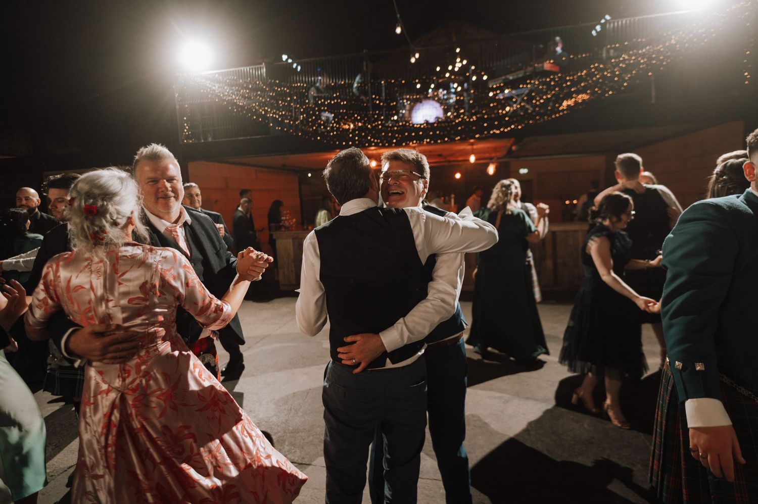 Wedding guests dance in formal attire and kilts at a Scottish-themed celebration.