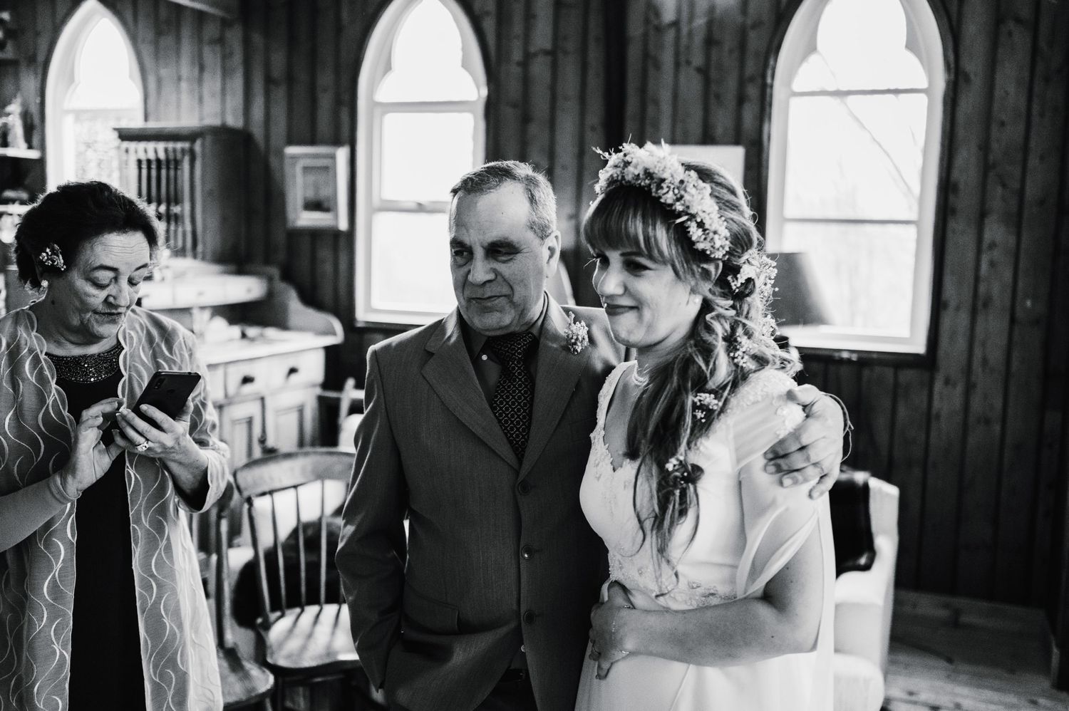 Black and white wedding photo showing intimate moment in church with arched windows.