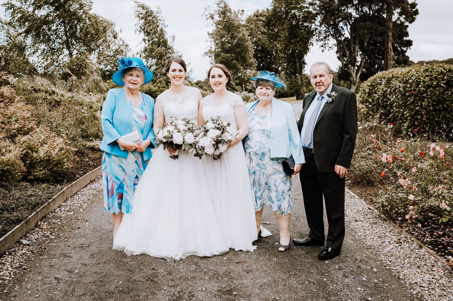Wedding group photo featuring bright blue and floral outfits with traditional white wedding dress.