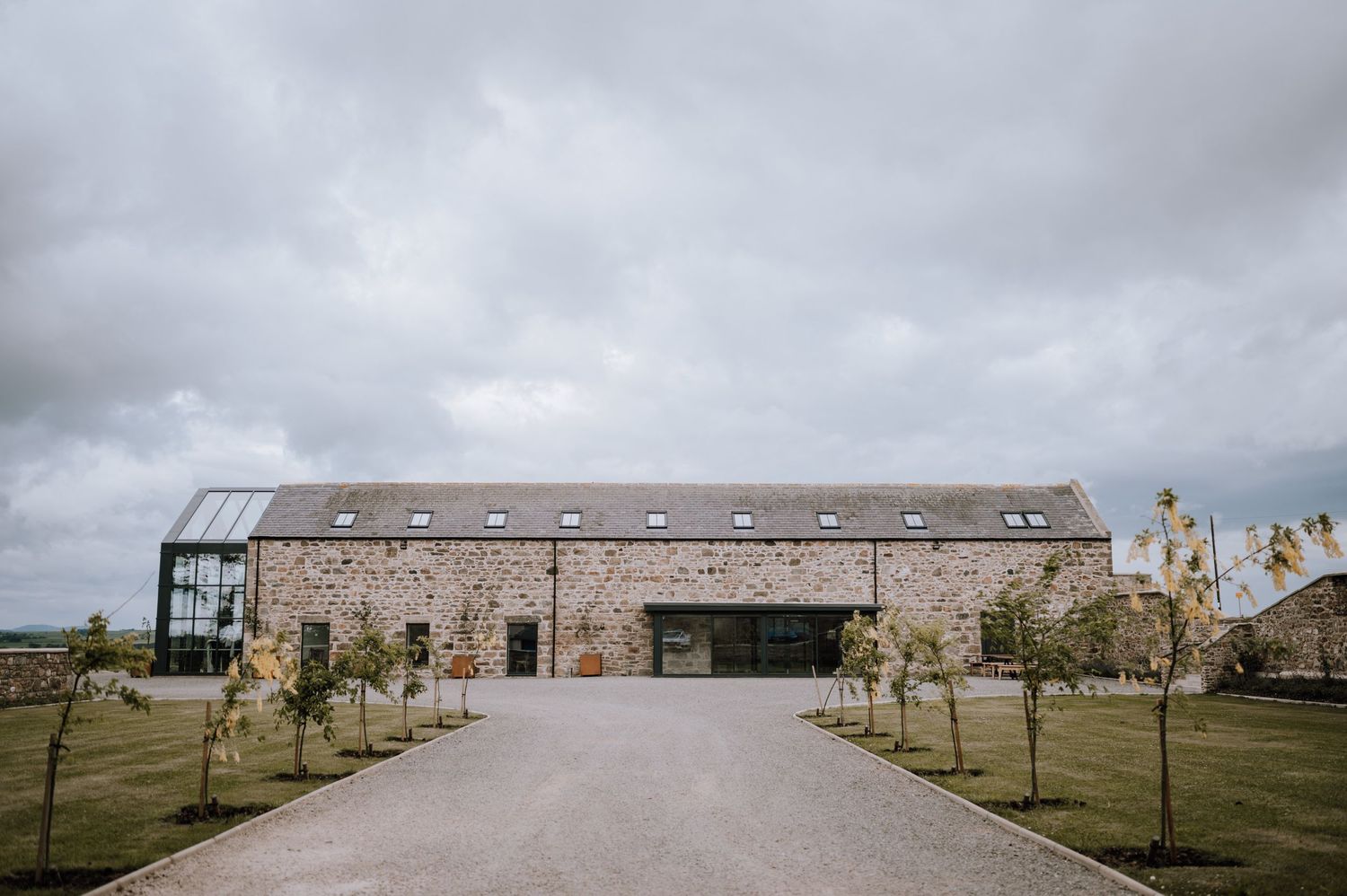 A modern converted barn venue with stone walls and a glass extension.