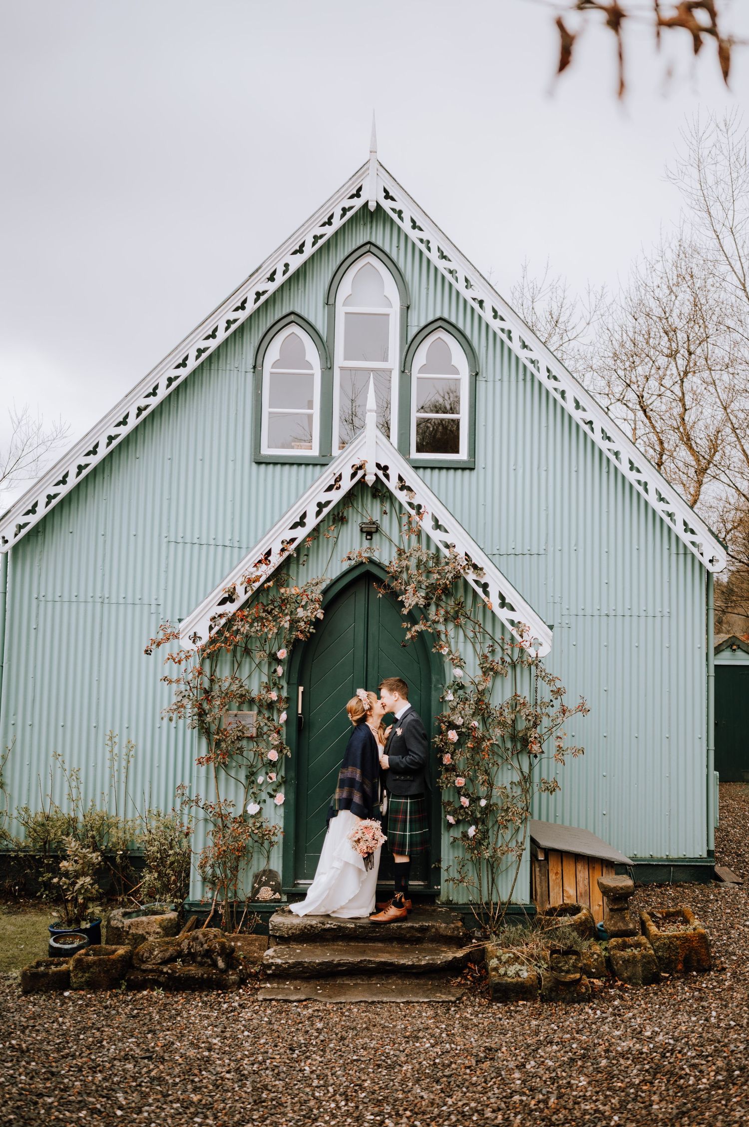 Mint green chapel with Gothic windows and vine-covered entrance arch creates charming wedding backdrop.