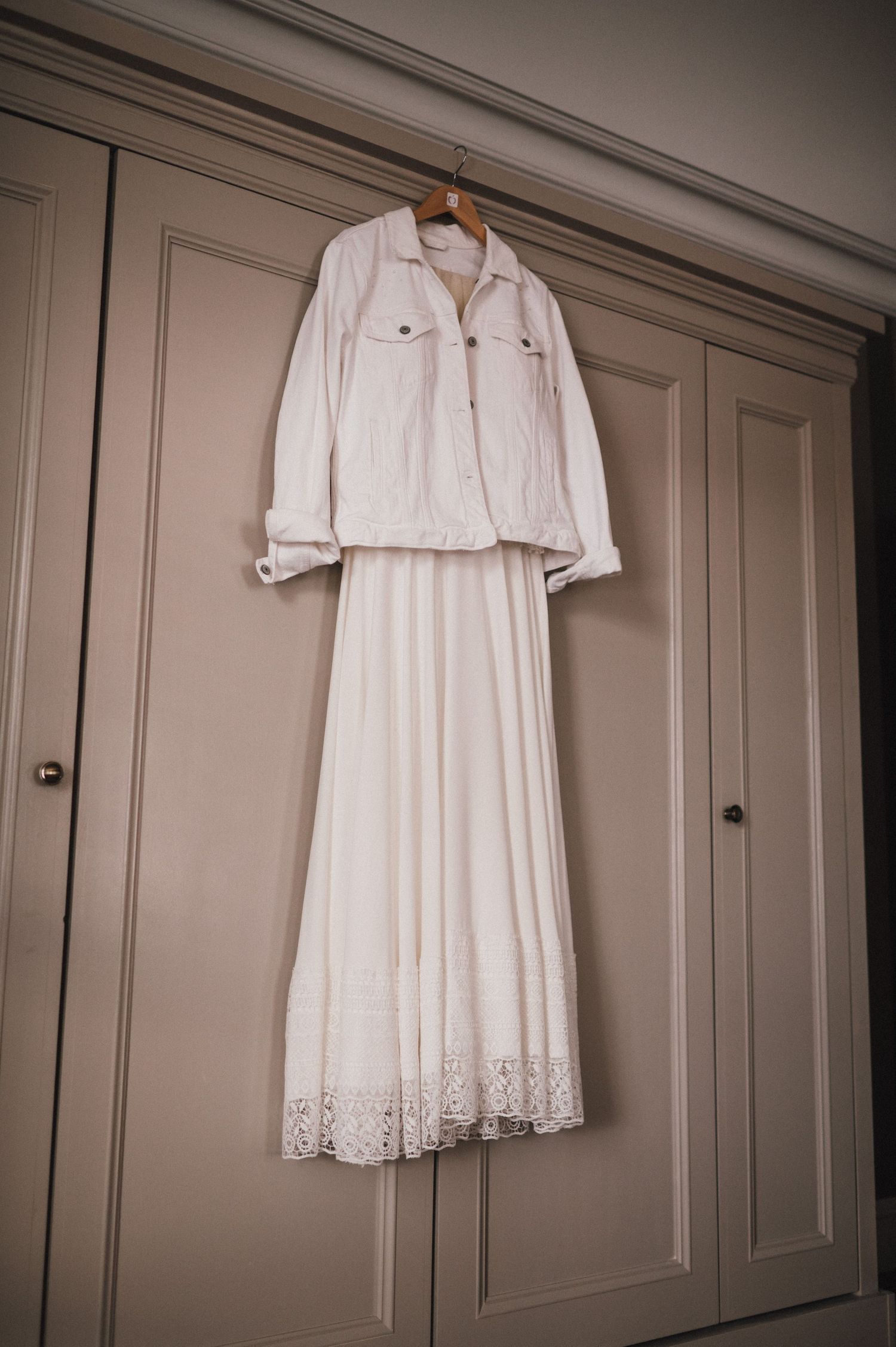Elegant white wedding dress and jacket hanging on built-in wardrobe.