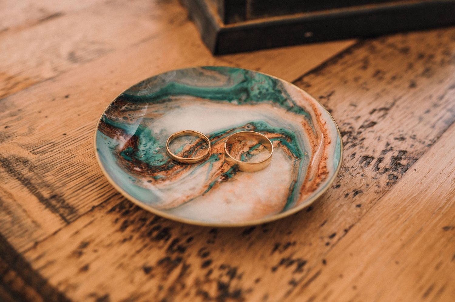 Wedding rings displayed on a decorative turquoise and white ceramic plate.
