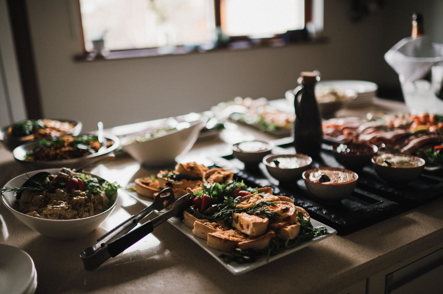 Rustic appetizer spread with various dishes and platters arranged on a dark table.