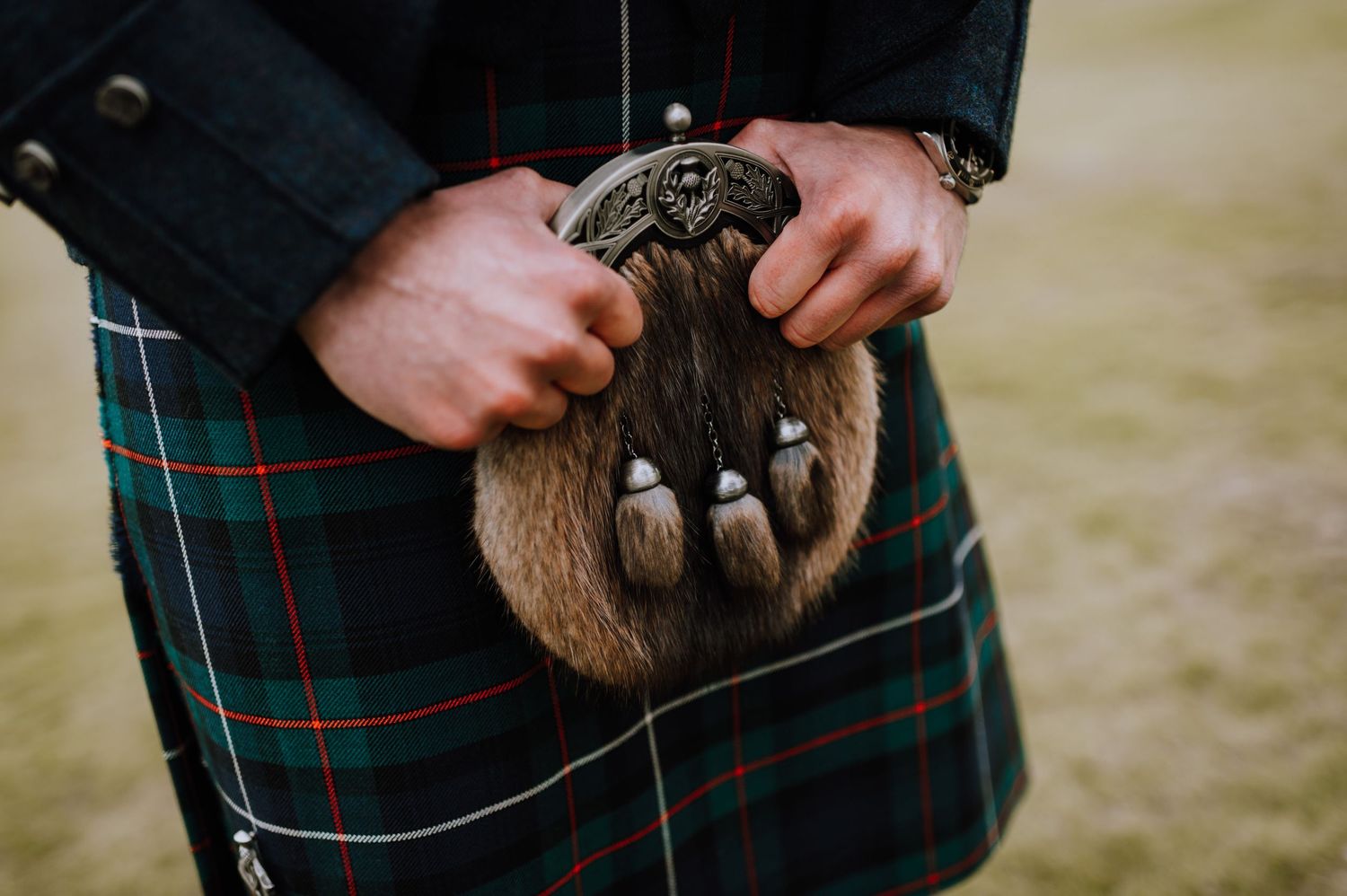 Traditional Scottish sporran with fur and silver detailing against a tartan kilt.