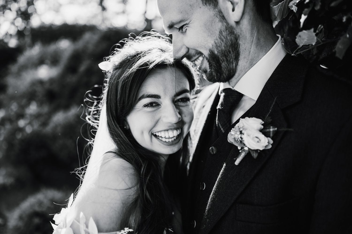 Close-up black and white wedding photo capturing genuine laughter and joy.