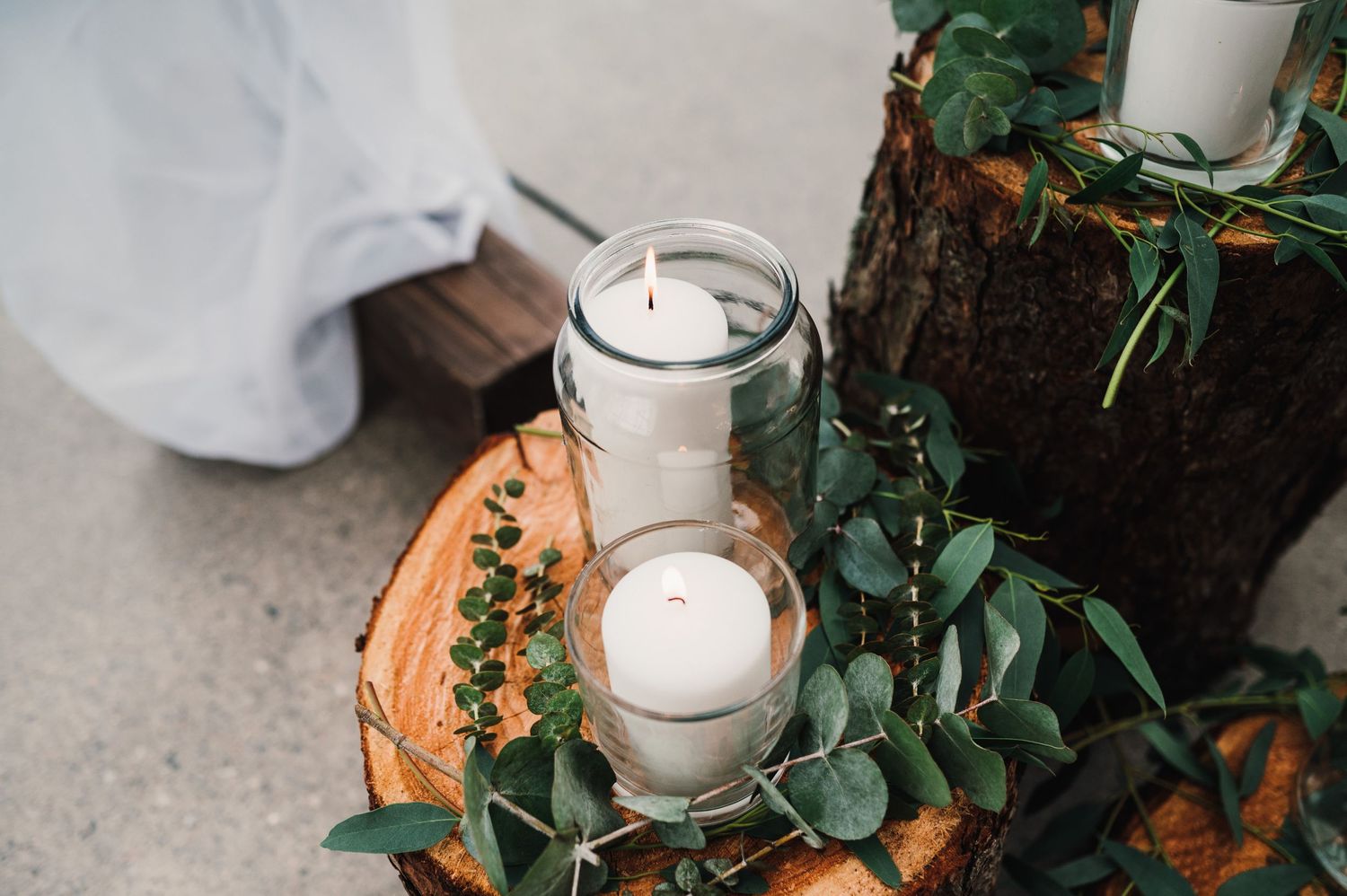 Glass jar candles surrounded by eucalyptus leaves create a romantic wedding decoration.