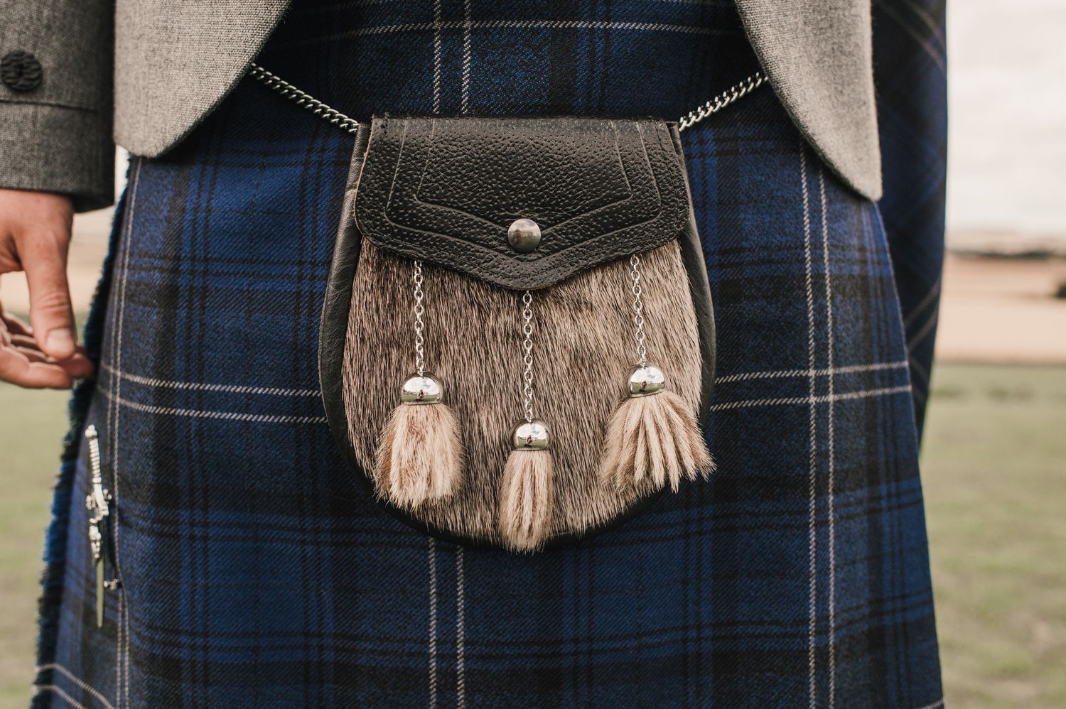 Traditional brown leather sporran with tassels worn against a blue tartan kilt.