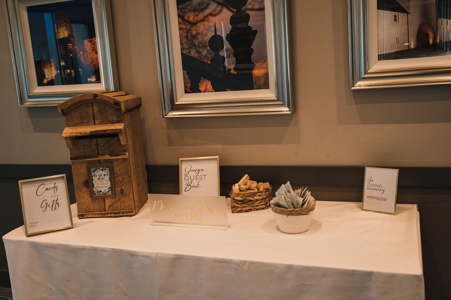 Wedding reception table with wooden decor elements and framed artwork on the wall.