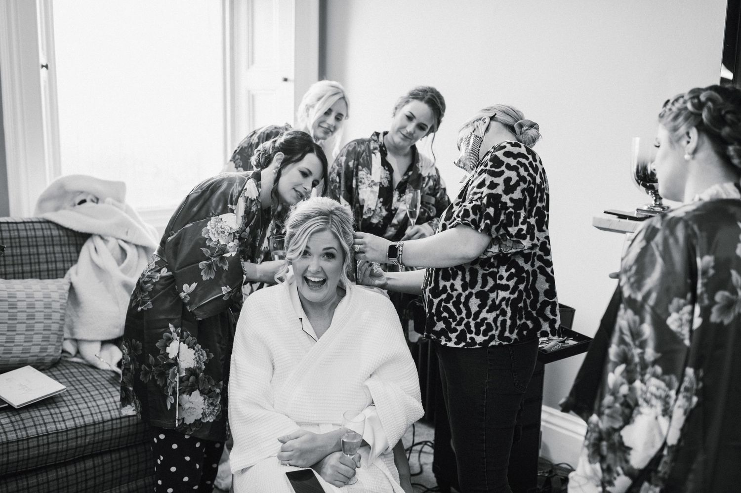Black and white photo of wedding preparation moment with group gathered around in patterned robes.