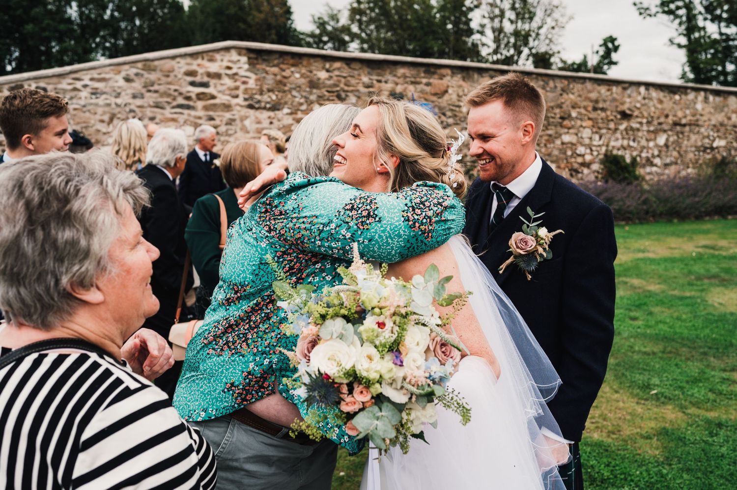 Celebratory moment with guests embracing during outdoor wedding reception.