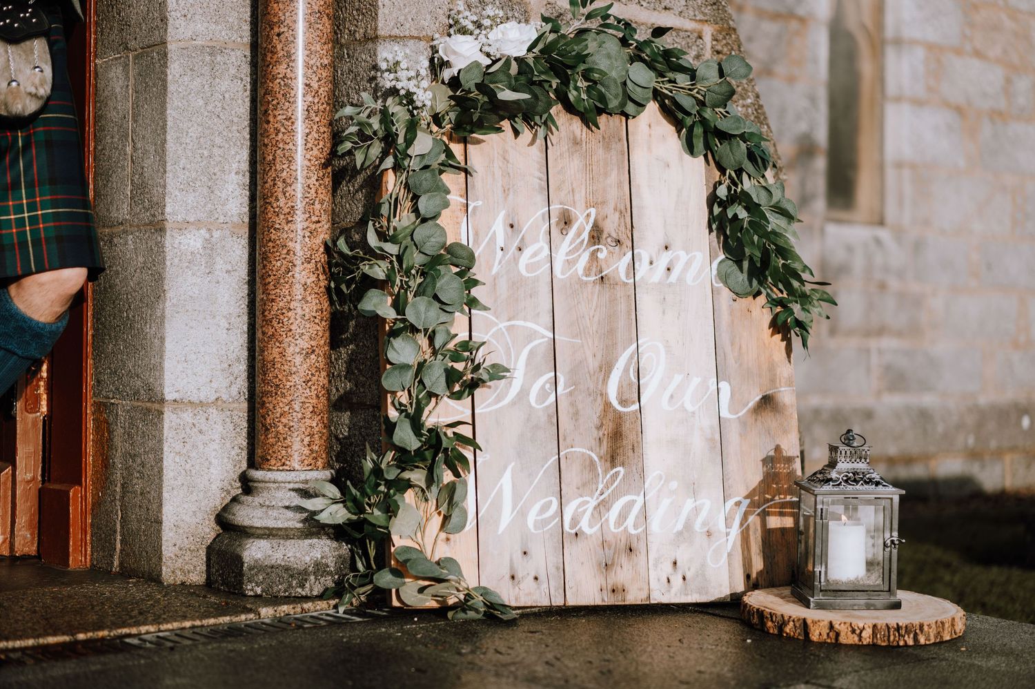 Rustic wooden door decorated with eucalyptus wreath and 'Mr & Mrs' text for wedding decor.