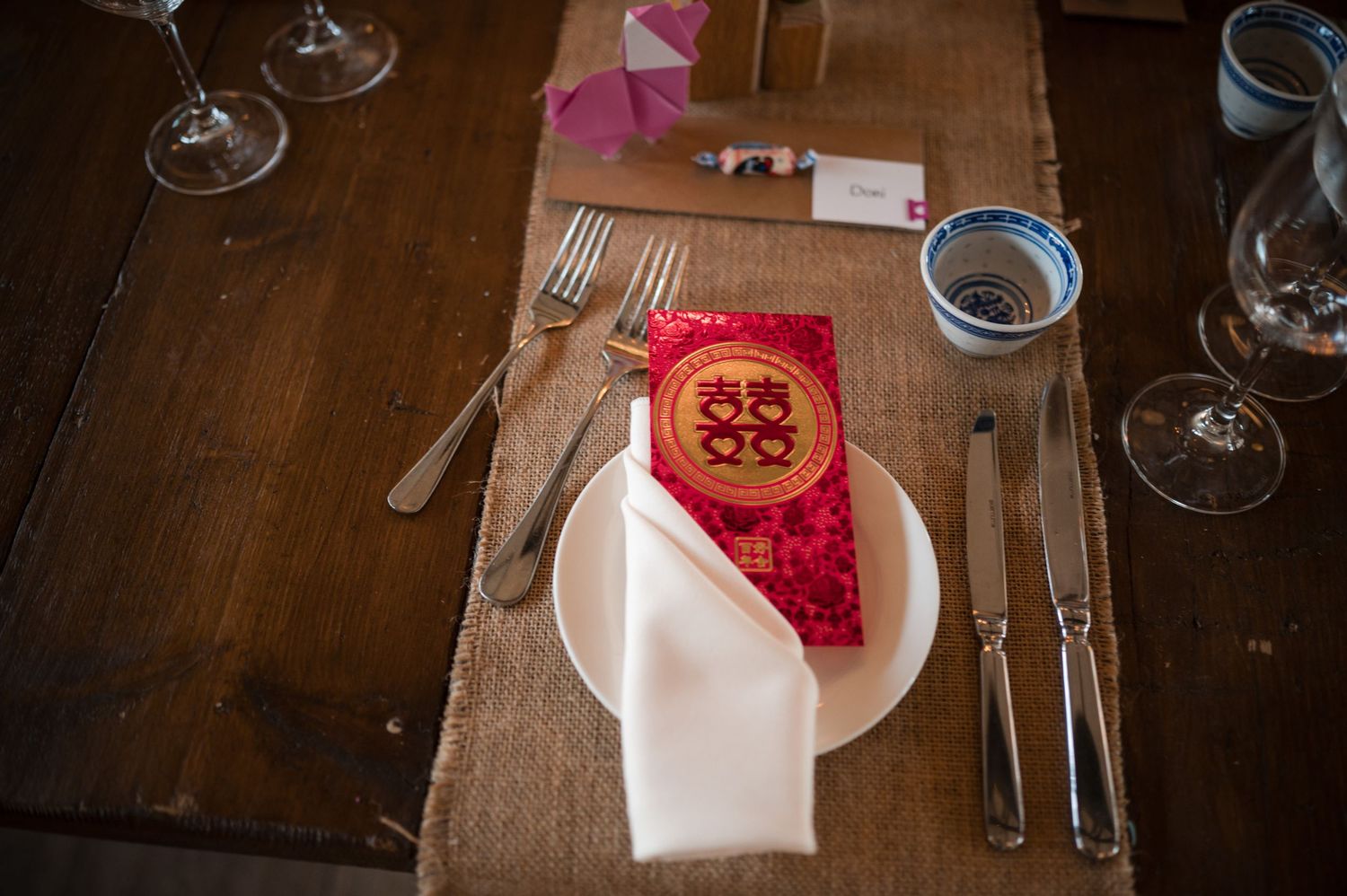 Elegant table settings with wine glasses and place settings on dark wooden surface.