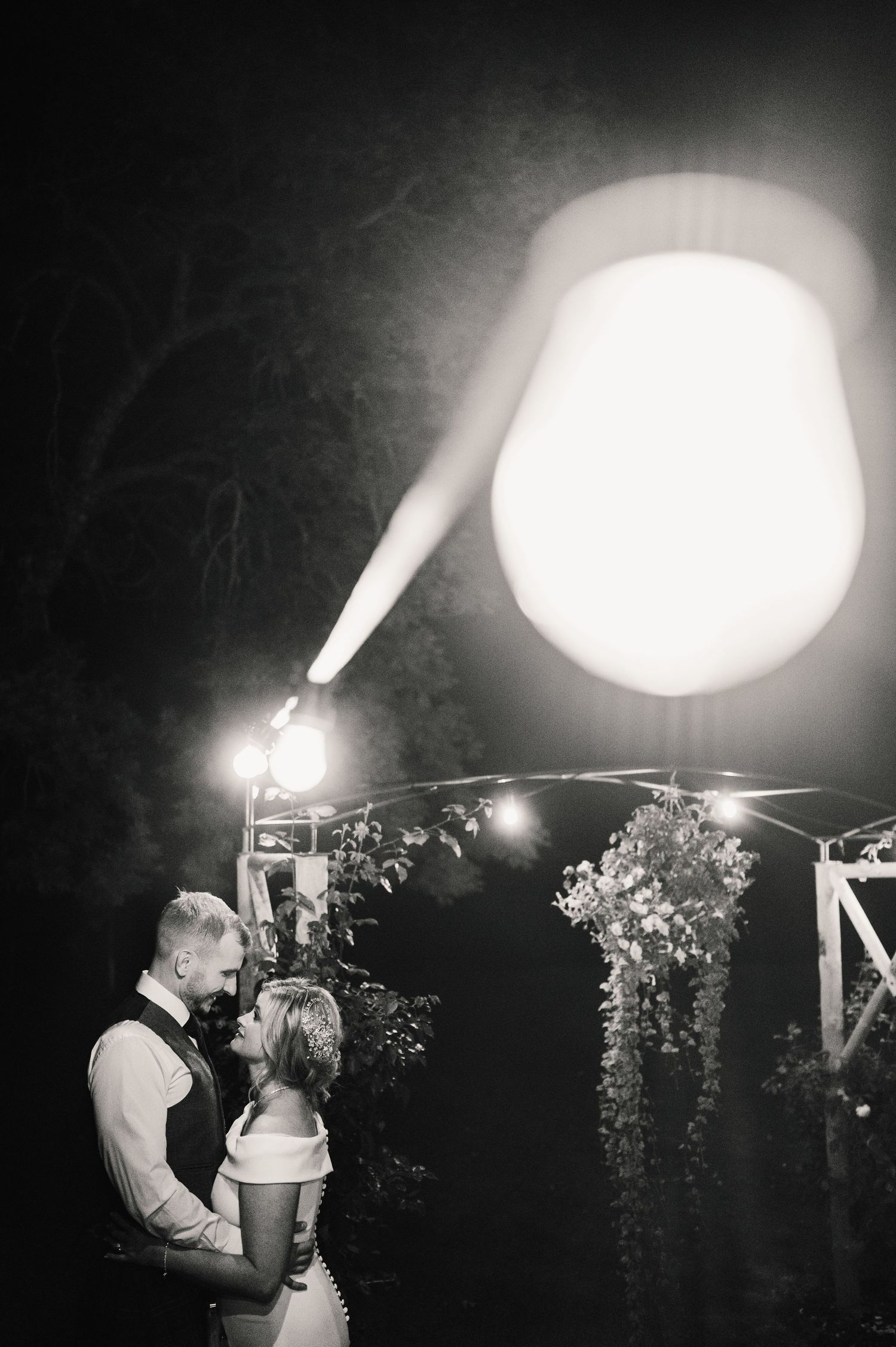 Romantic black and white nighttime wedding photos under dramatic lighting.