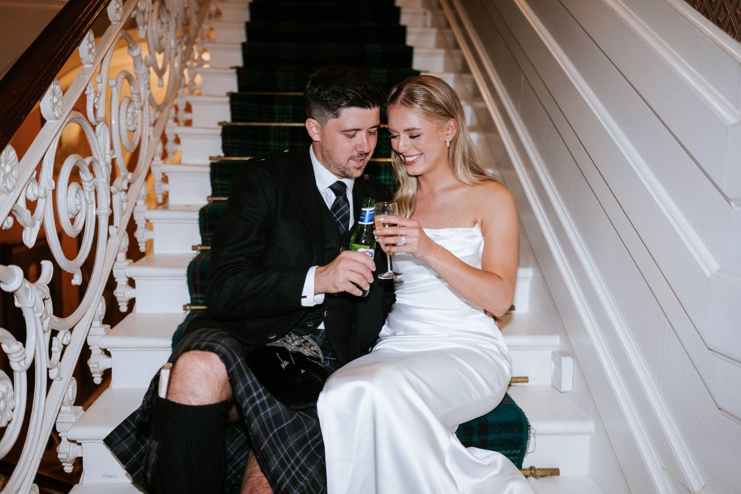 Couple walks along ornate staircase during wedding celebration.