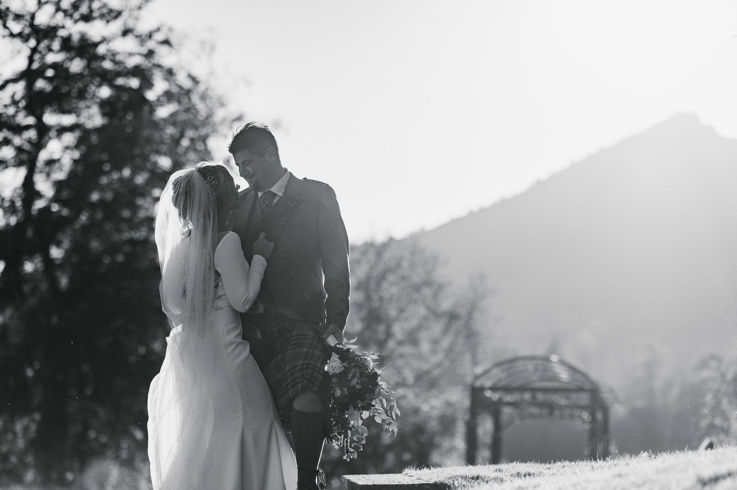 Aberdeen Wedding Photography. A couple embraces in black and white photography with mountain peaks in the background.