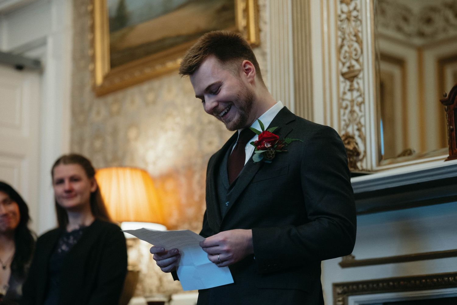 Drumtochty Castle  Wedding Photography. Speaker delivering remarks while holding papers in an elegant room with gilded mirrors.