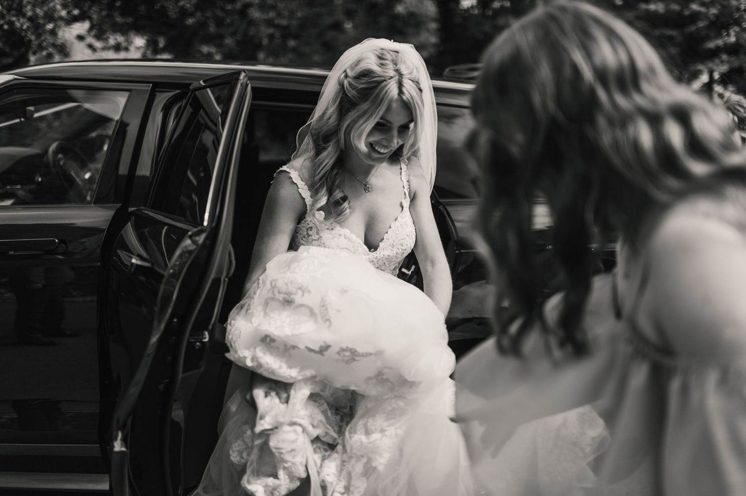 Black and white photograph of wedding preparations outside a vintage car.