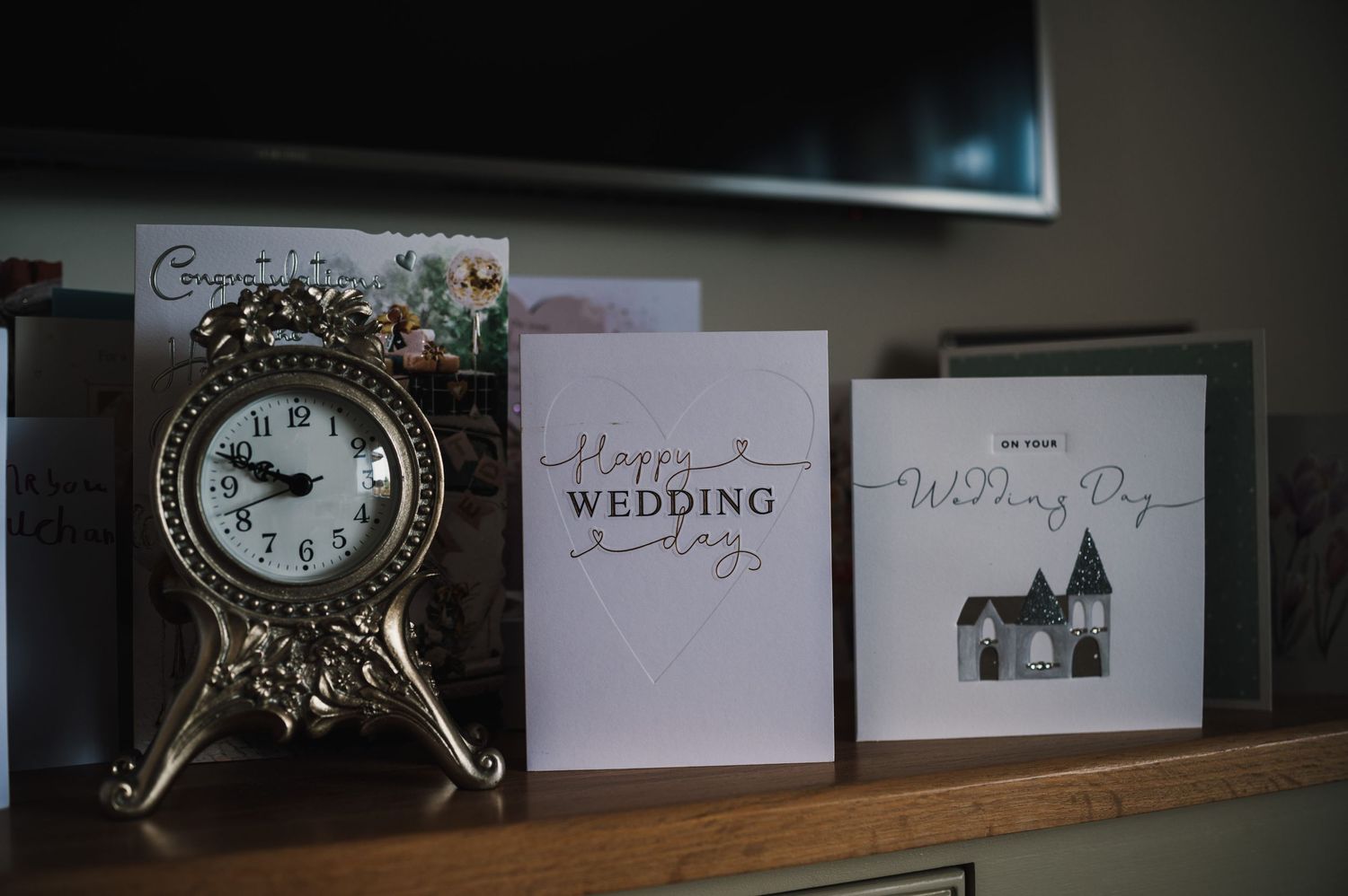 Vintage clock and wedding cards displayed on wooden shelf.