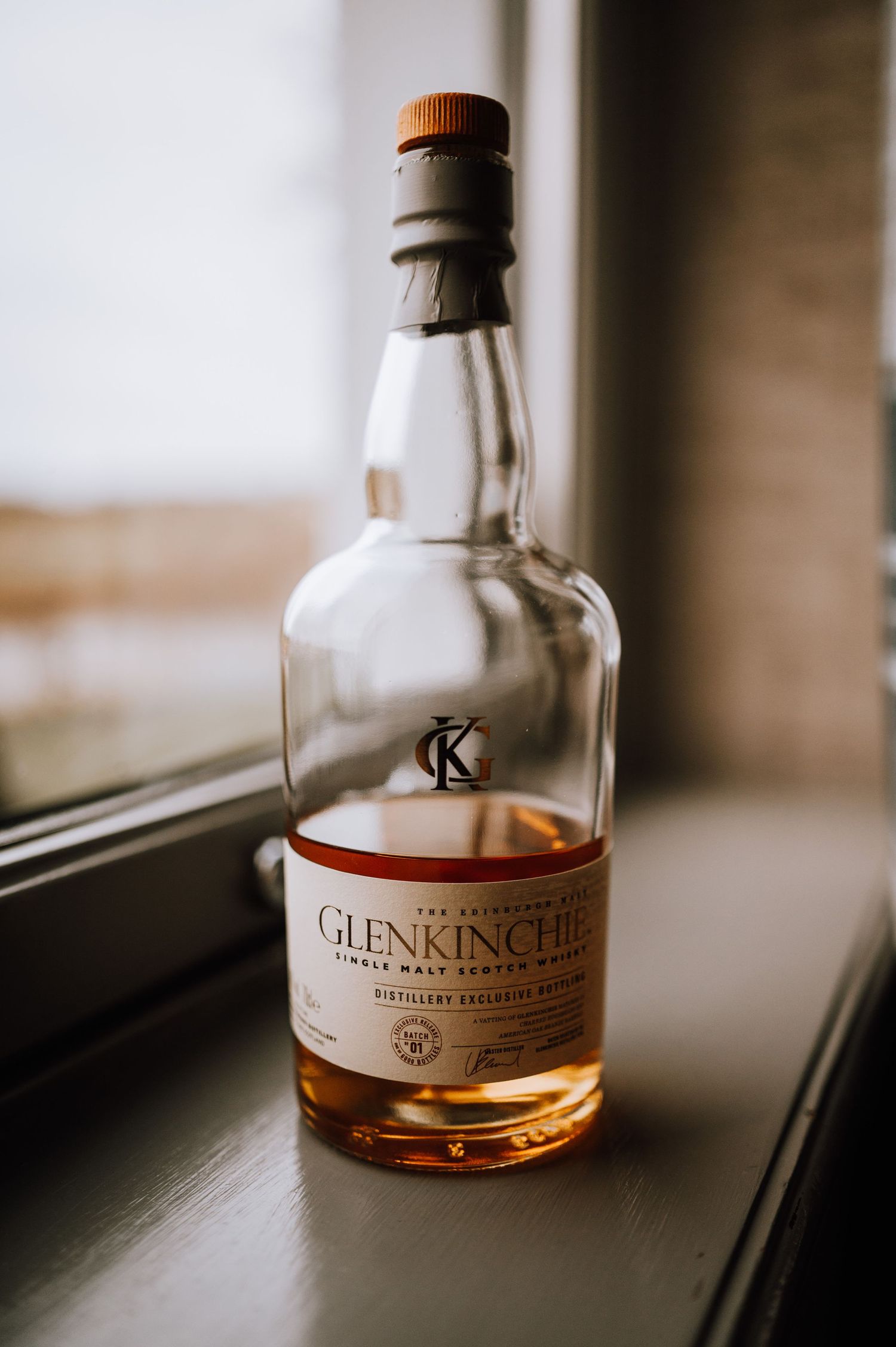 A bottle of Glenkinchie whisky sits on a windowsill in natural light.