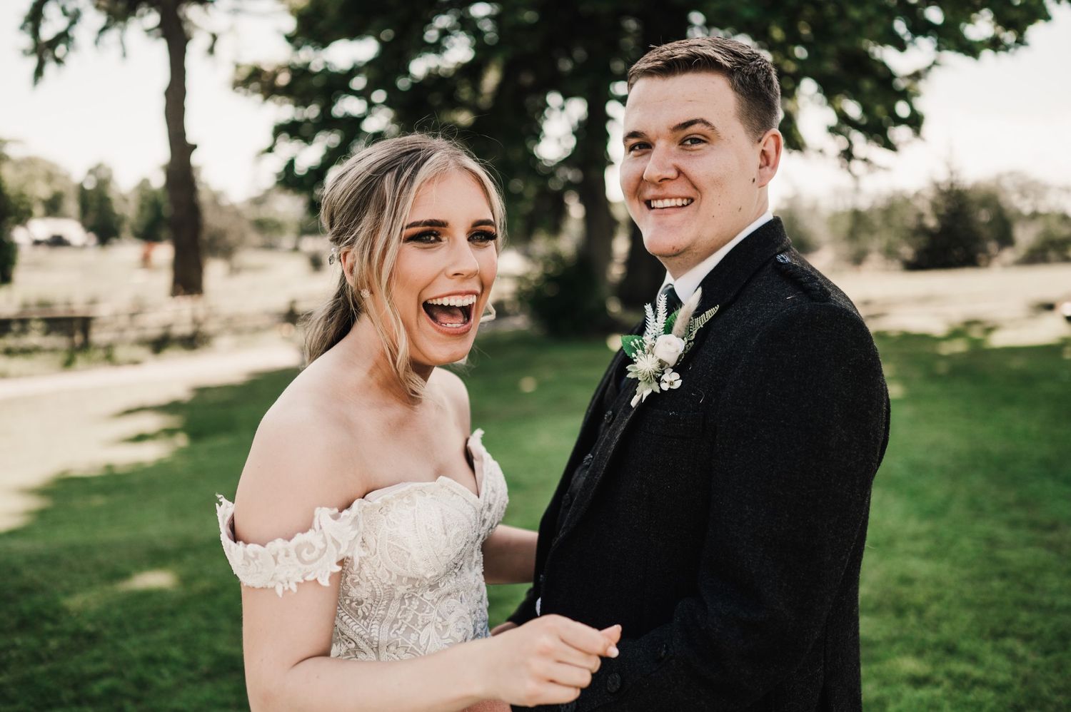 A joyful candid wedding moment captured outdoors with laughter and natural light.