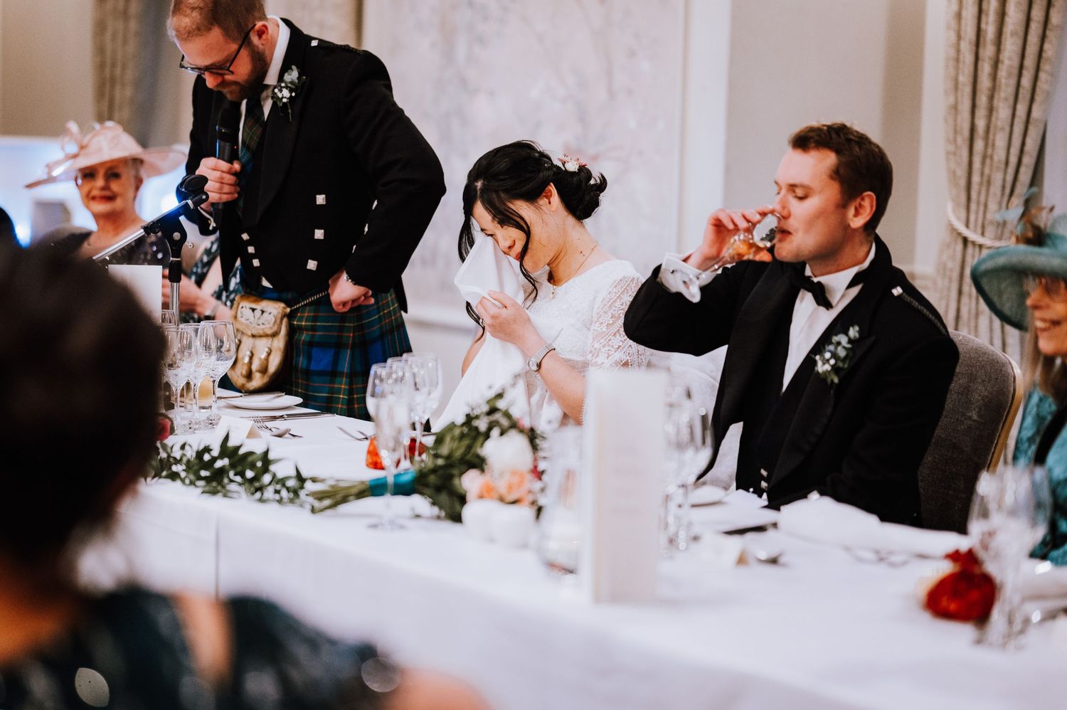 Reception guests raise glasses in a toast during formal dinner celebration.