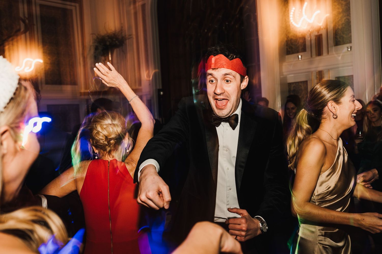 Energetic wedding reception dancing with guests in formal attire enjoying the celebration.
