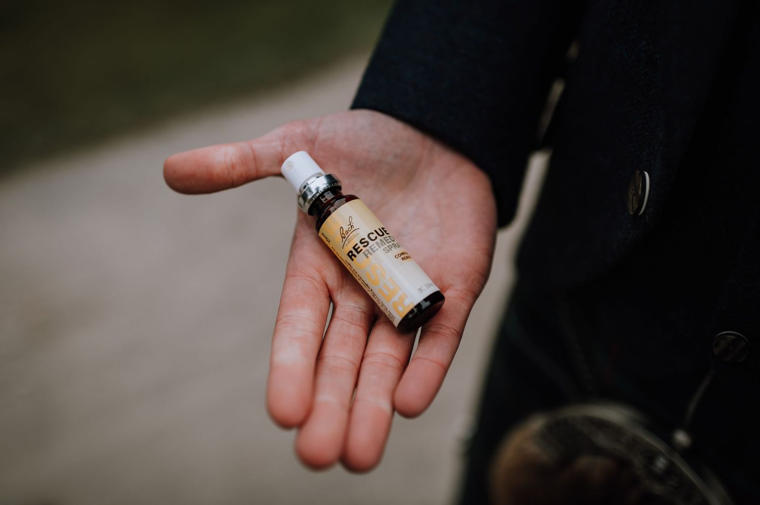 A small vintage glass vial held in palm against formal attire.