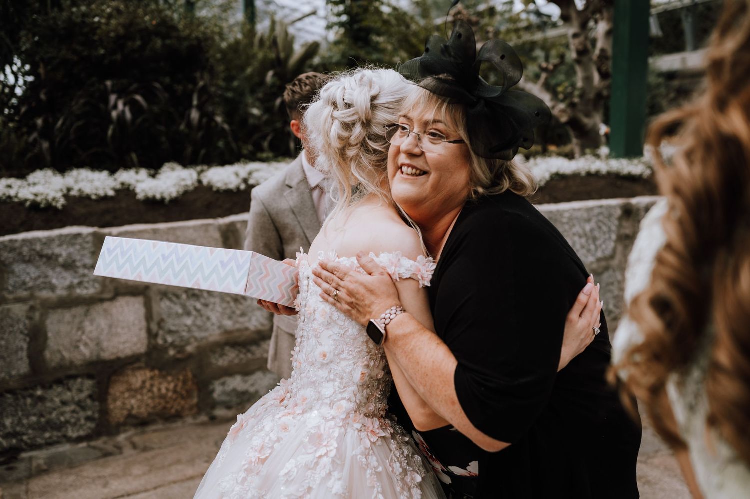 Wedding guests share warm hugs and emotions during an outdoor celebration.