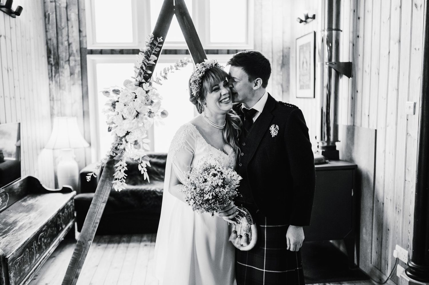 Black and white wedding portrait under decorative triangle arch with natural window light.