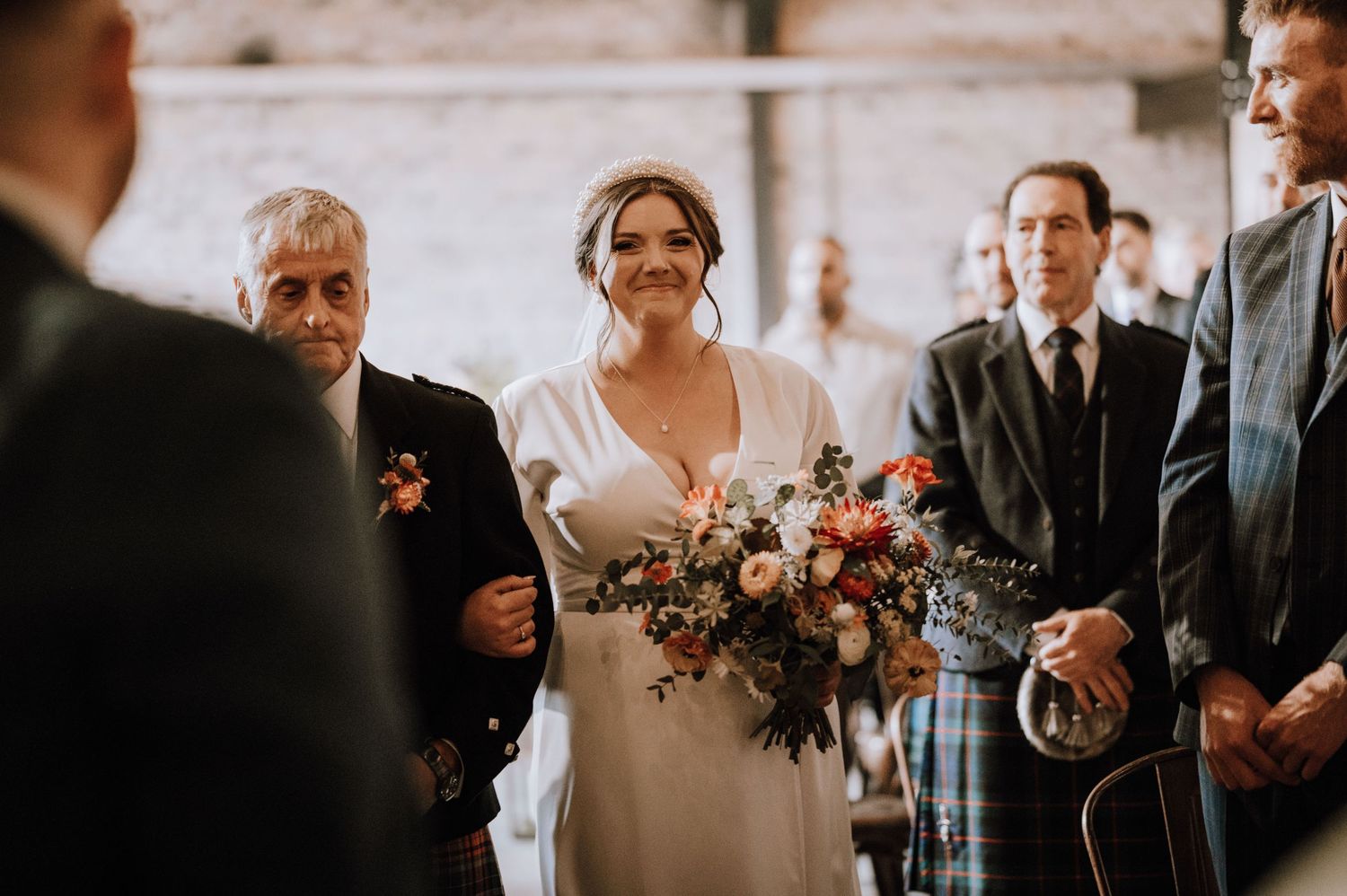 Wedding ceremony taking place in rustic indoor venue with natural light streaming through windows.