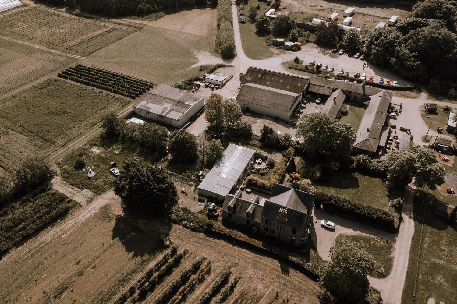 Drone shot of a historic property complex with surrounding farmland and outbuildings.