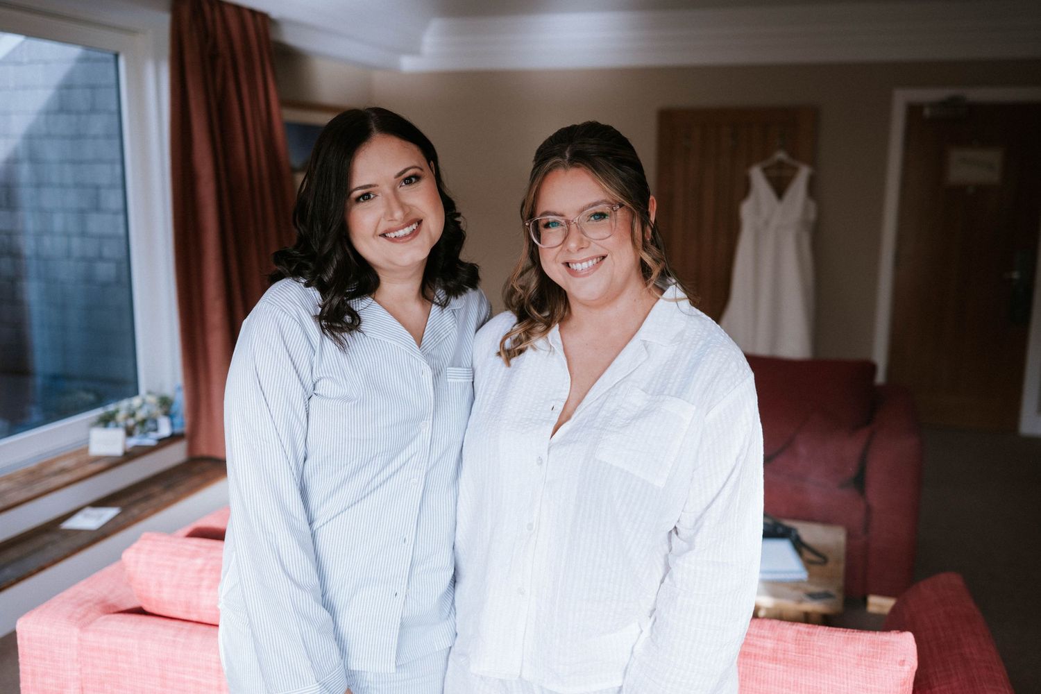 People in white robes smile and pose together during wedding day preparations.
