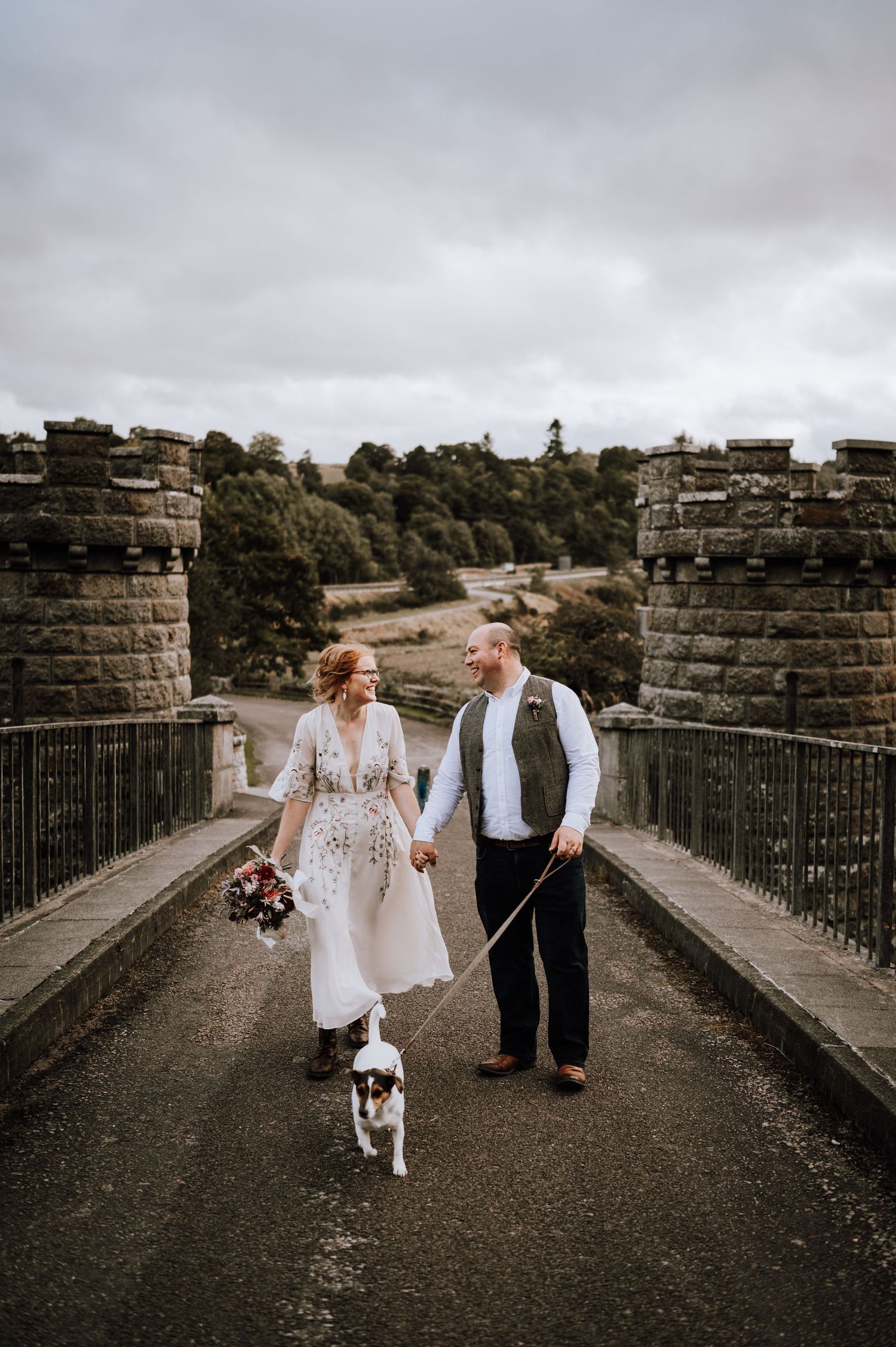 Joyful candid moment between couple on stone bridge during wedding celebration.