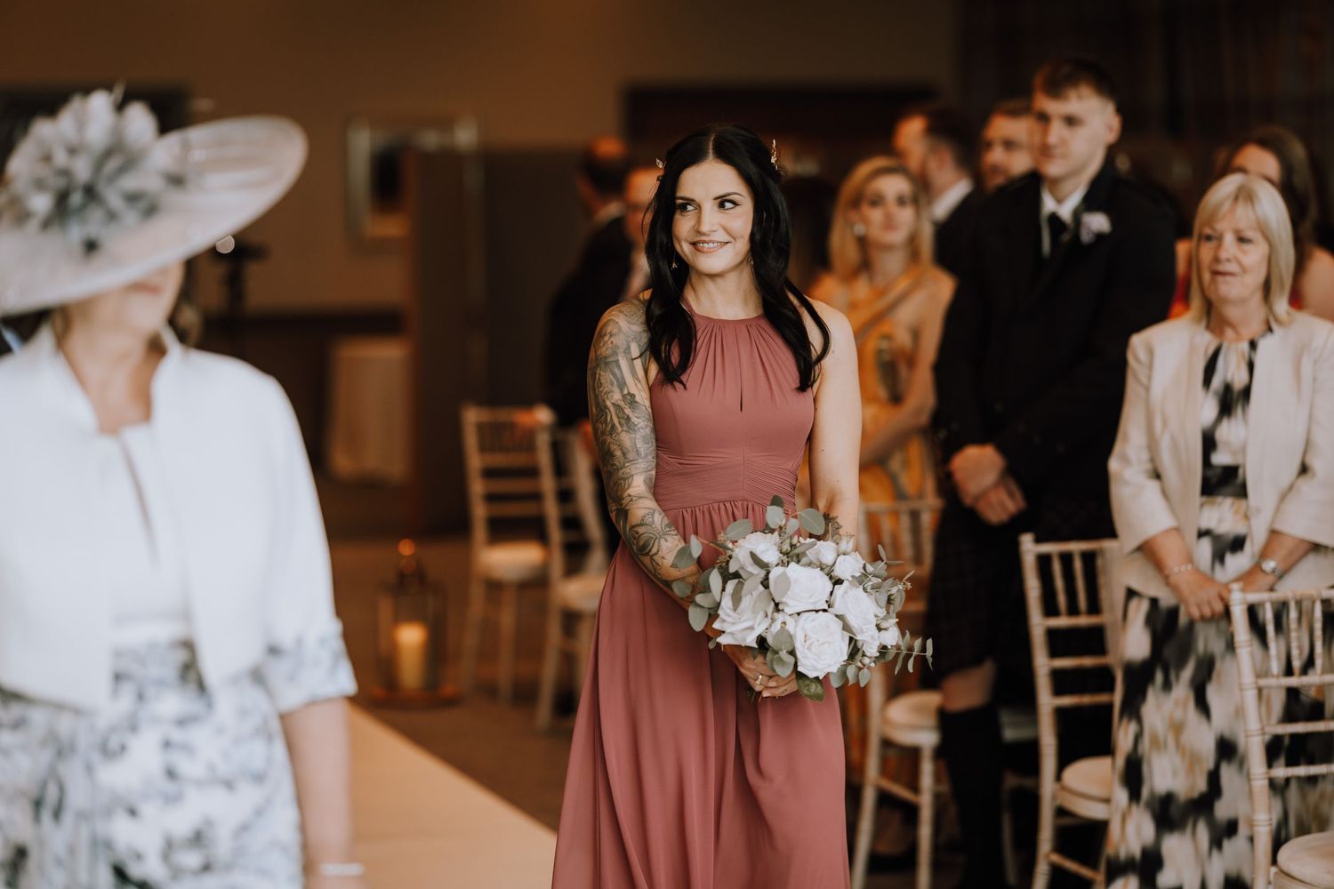 Wedding ceremony procession with guests in formal attire and elegant decor.