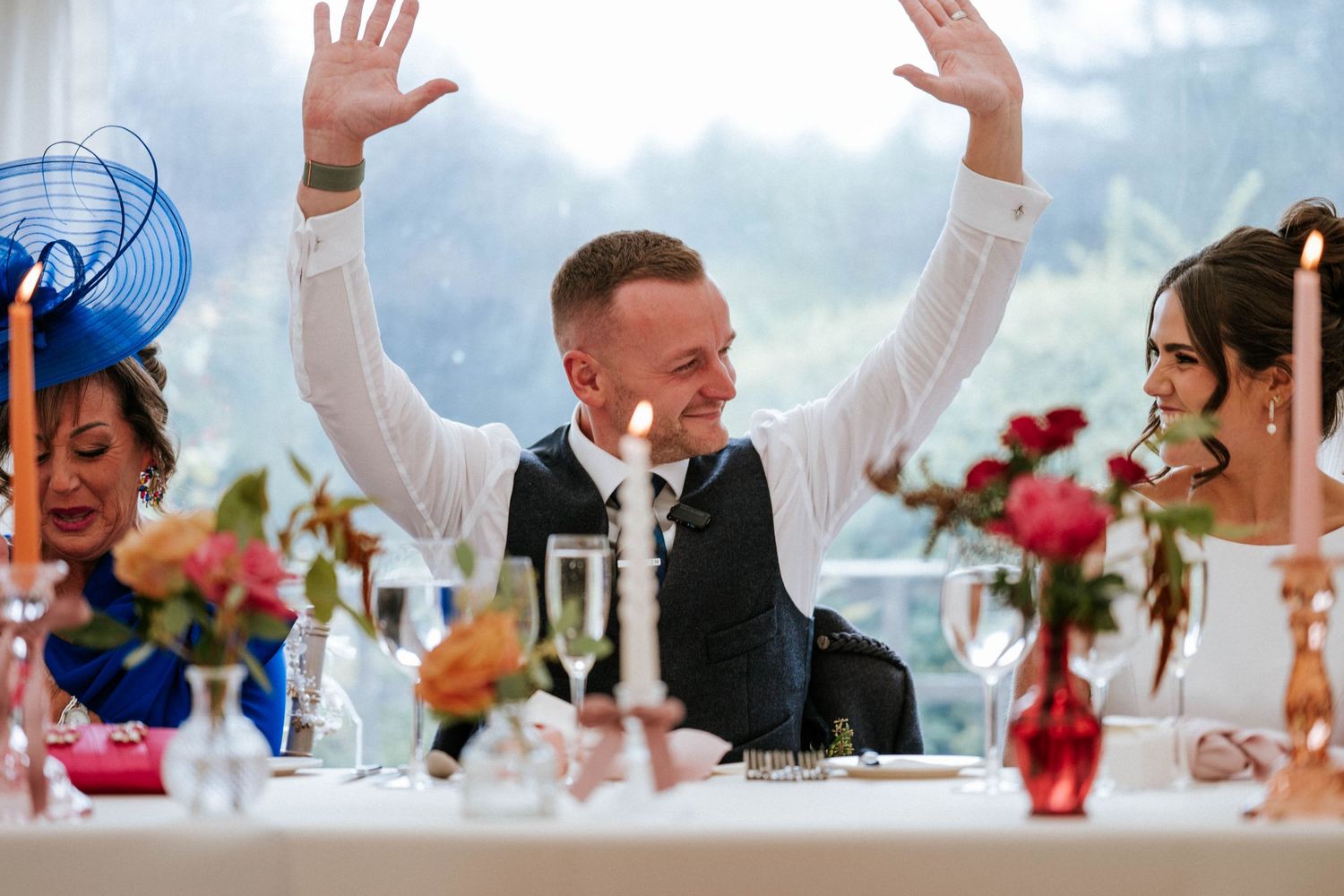 Celebratory moment at a wedding reception with raised hands under a white tent.