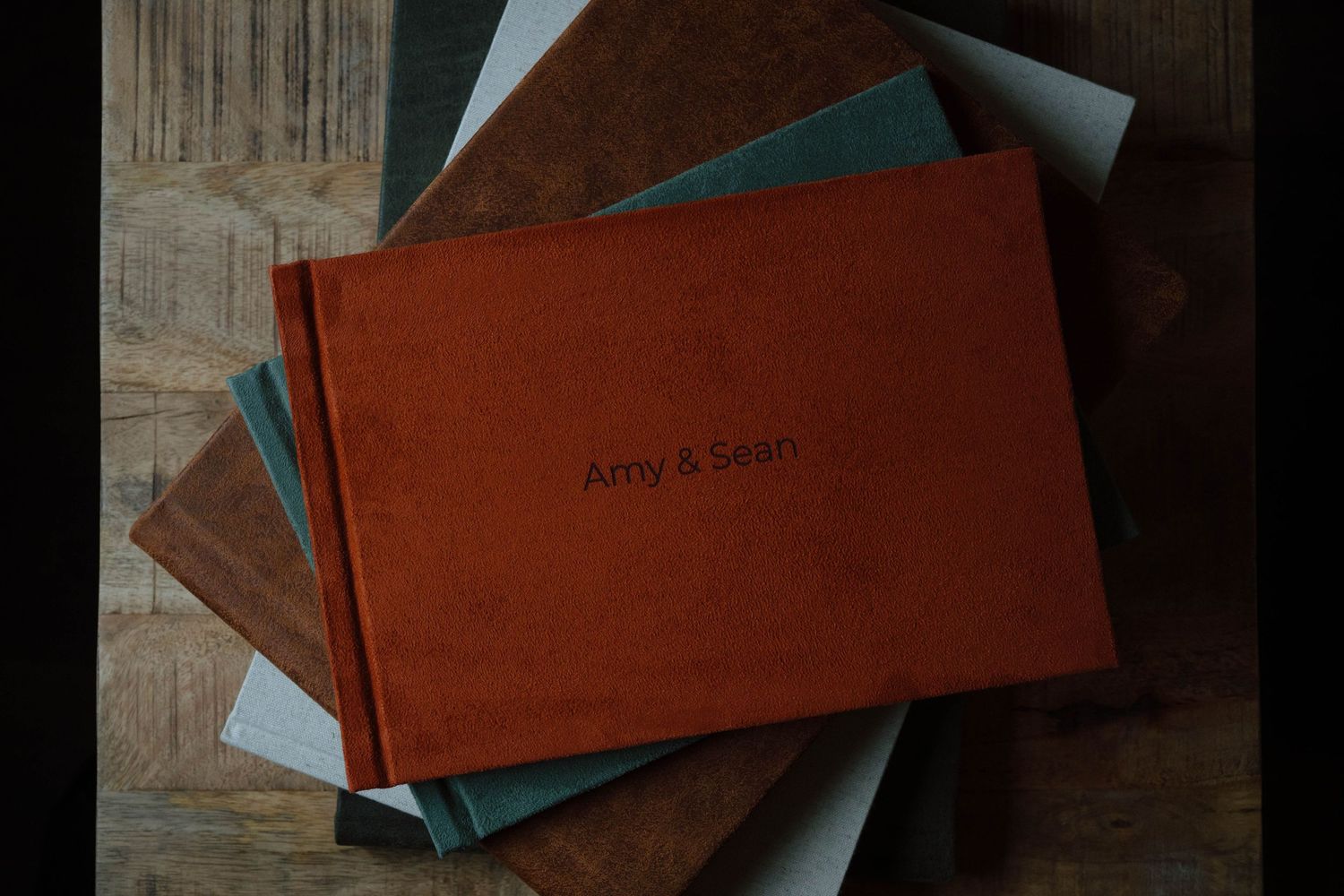 Brown leather photo album or book covers arranged on wooden surface in moody lighting.