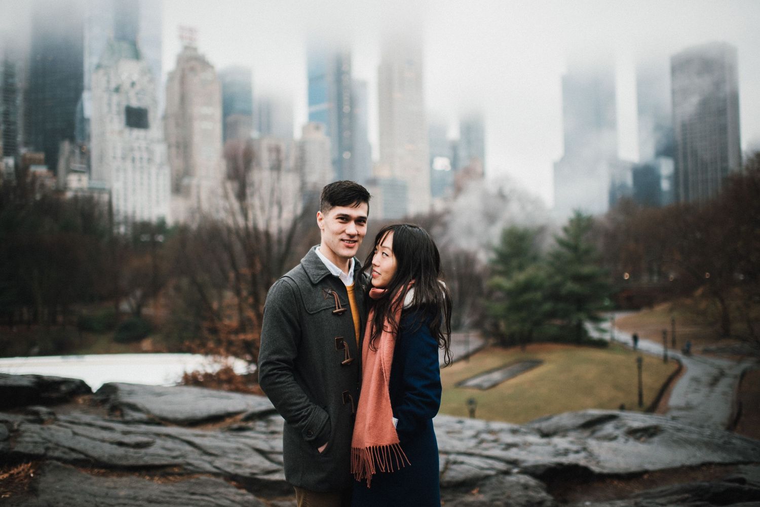 A romantic winter moment with a couple against the foggy Manhattan skyline in Central Park.
