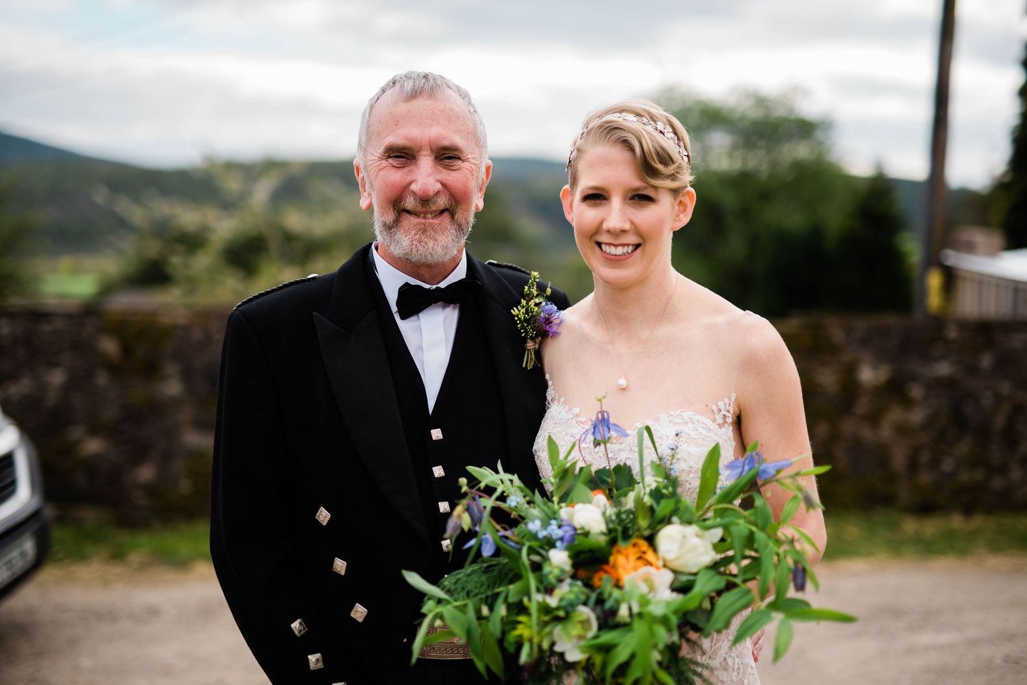 Scottish wedding portrait outdoors with traditional formal attire and bright bouquet.