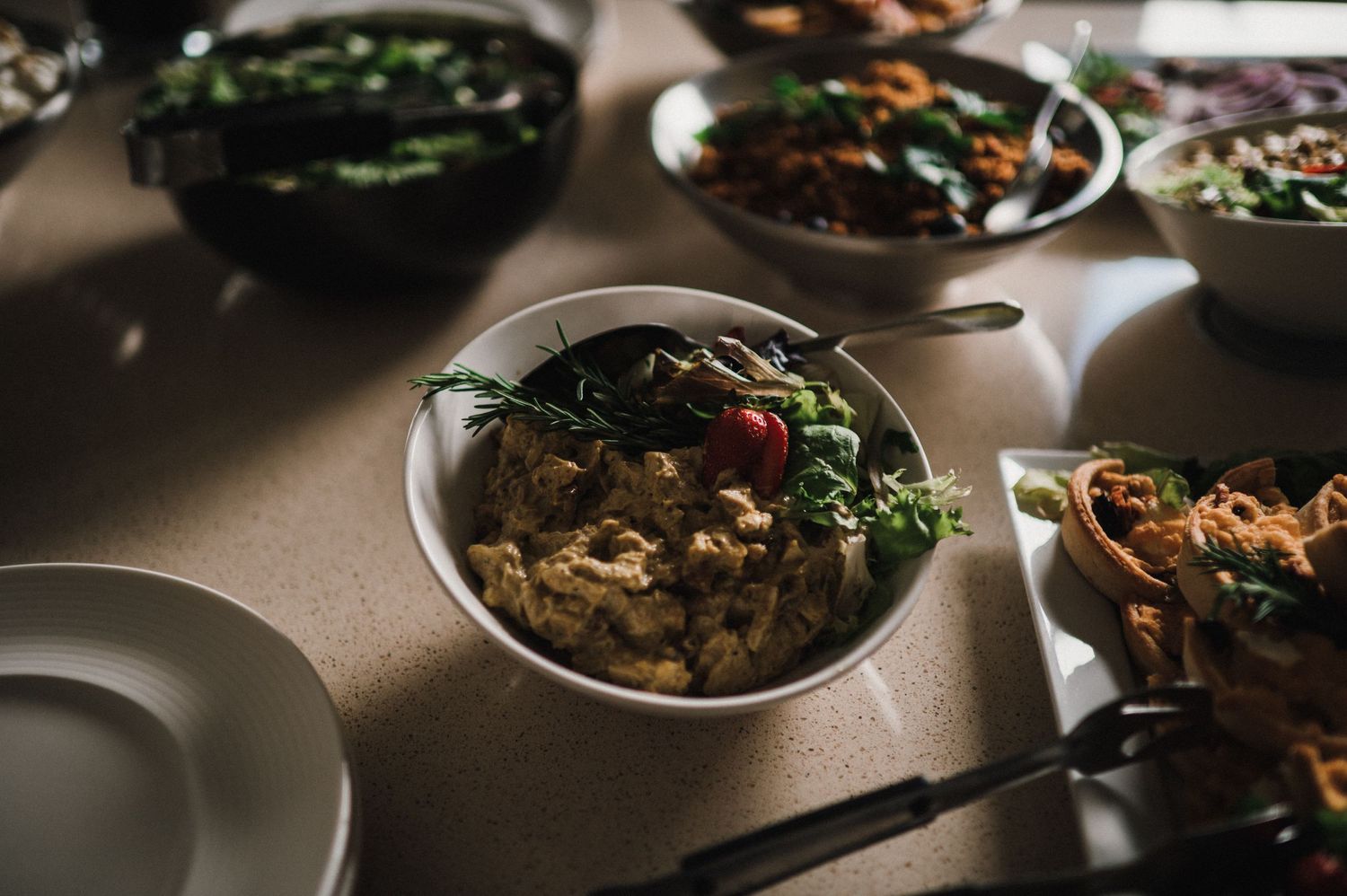 Bowls of mixed salads and dishes served on a dimly lit dining table.