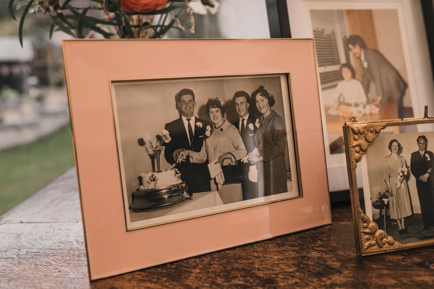 A vintage sepia photograph displayed in a peach-colored frame on a wooden surface.