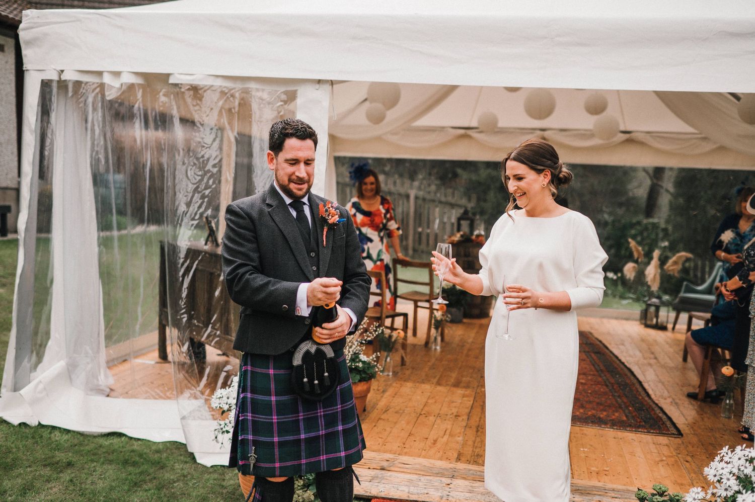 Couple performs traditional Scottish wedding ceremony with drinks under white tent.