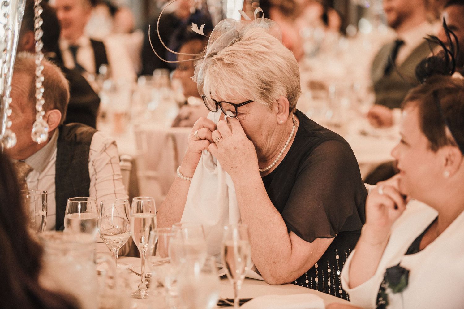 Guest at wedding reception showing emotional response during speeches.