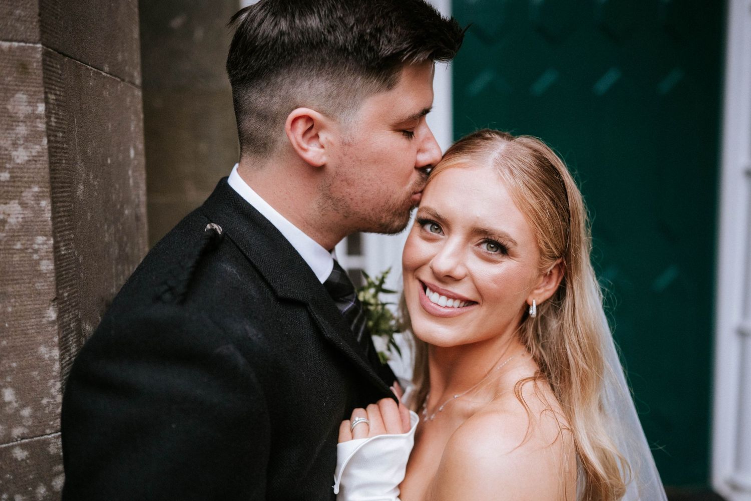 Intimate moment between newlyweds in front of a historic stone building entrance.