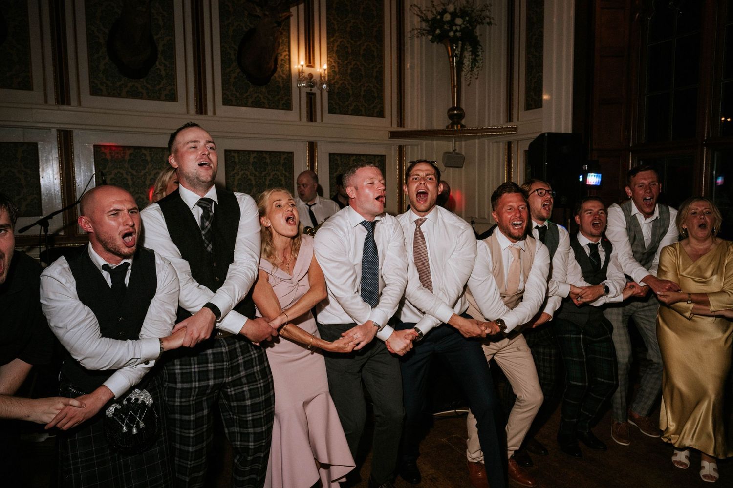 Wedding reception guests dancing and celebrating together on a dance floor in formal attire.