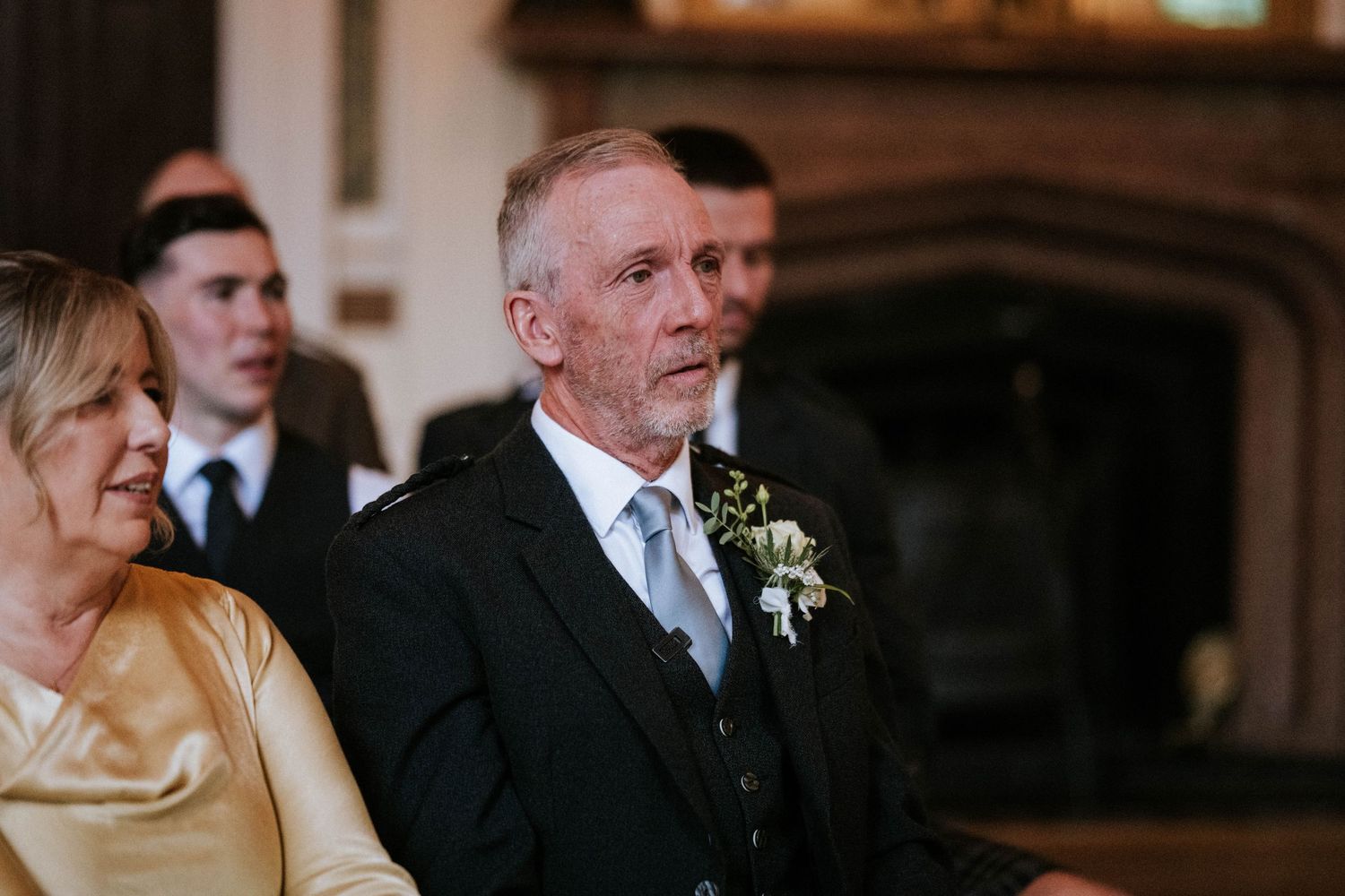 Elegant wedding ceremony in a warmly lit indoor venue with formal attire and floral decorations.
