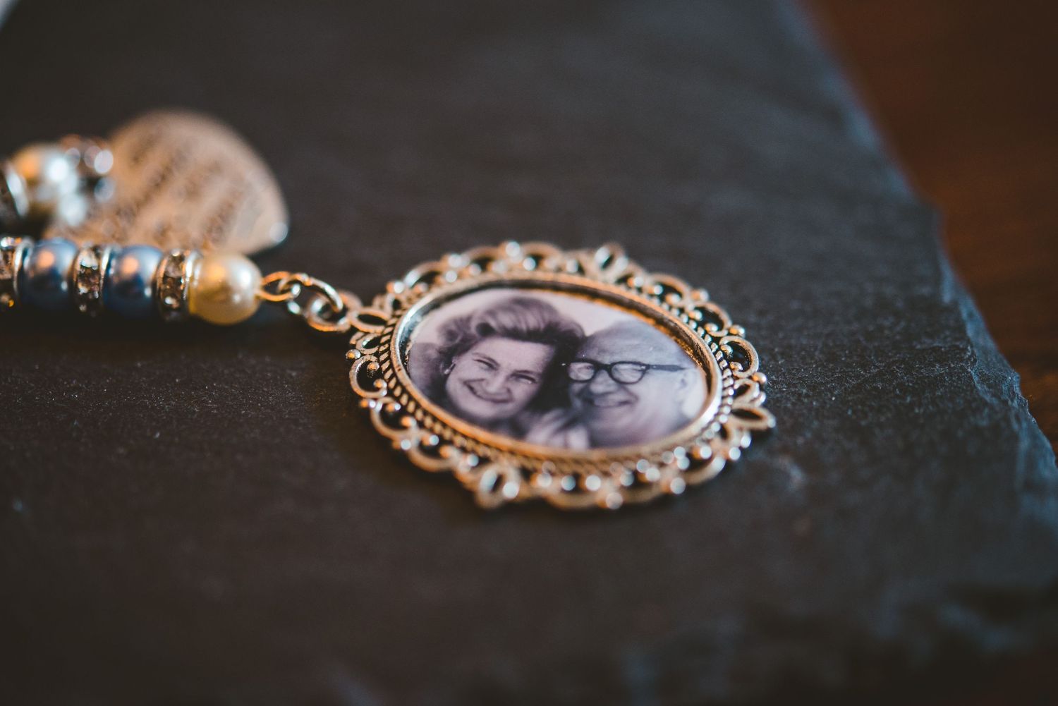 Vintage-style photo lockets and pendants with ornate frames displayed on dark textured surface.