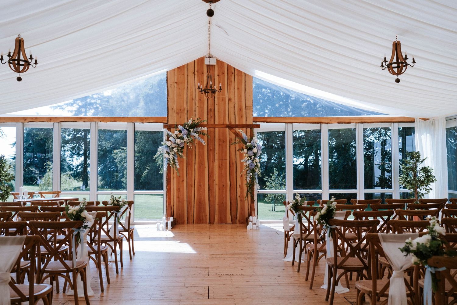 Empty wedding venue with white draped ceiling and wooden details.